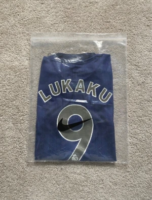 Manchester United Lukaku #9 matchtröja - Säljer en officiell Manchester United fotbollströja från Adidas med Lukaku och nummer 9 på ryggen. Tröjan är mörkblå med guldiga detaljer, Chevrolet-logga på bröstet och Premier League-märke på ärmen. Materialet är lätt och ventilerande polyester.