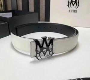 AMIRI Bälte - Snyggt vitt bälte från Amiri i skinn med bred rem och en stor, silverfärgad metallspänne med Amiris ikoniska logga. Perfekt accessoar för att lyfta din outfit med en lyxig och modern touch.