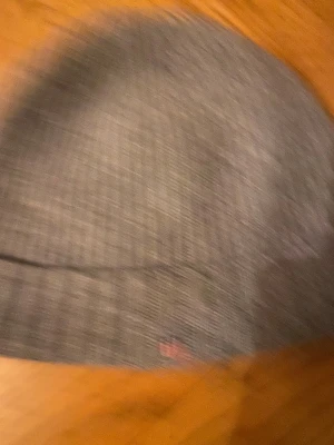 Grå ribbstickad mössa från GANT - Snygg grå ribbstickad mössa från GANT. Klassisk modell med uppvikt kant och diskret logga. Perfekt för kyliga dagar och enkel att matcha med olika outfits. Tillverkad i mjukt material som håller dig varm.