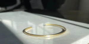 Enkelt guldigt armband i mässing  - Stilrent och minimalistiskt armband i guldig metall med öppen design. Armbandet har en lätt hamrad yta som ger en diskret textur och extra glans. Perfekt för dig som gillar enkel men snygg accessoar.