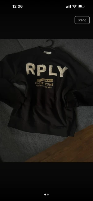 Svart sweatshirt från Replay med fluffiga bokstäver - Svart sweatshirt från Replay med stora, fluffiga vita bokstäver 'RPLY' på bröstet och gul text under. Klassisk rund hals och långa ärmar. Skön och avslappnad passform, perfekt till jeans eller joggers.