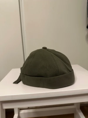 Mössa / Keps utan skärm - Säljer ”mössor” i olika färger med cool knytning baktill och uppvikt kant. Mössan har en rundad form och är tillverkad i slitstark bomull. Perfekt för dig som vill ha en unik och street-inspirerad look. En patch syns på sidan för extra detalj.
