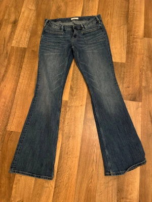 Blå bootcut jeans från Perfect Jeans - Snygga blå jeans från Perfect Jeans i storlek 38. Modellen har klassisk bootcut med utsvängda ben och fem fickor. Jeansen är tillverkade i slitstarkt denim och har en normal passform med midwaist. Perfekt för dig som gillar retrovibbar och bekväma jeans.