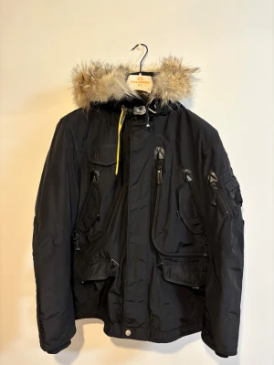 Svart Parajumpers parkajacka med päls - Dags att sälja min fina Parajumpers jacka efter några års sparsam användning pga att den ej passar i storlek längre.   Avtagbar äkta päls.  Extra knappar. Tillhörande galge.  Originalkvitto finns.   Jackan kan postas till hela Sverige alternativt mötas upp i Stockholmsområdet.   Pris kan diskuteras vid snabbaffär!