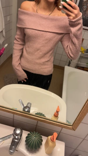 Ljusrosa offshoulder stickad tröja - Superfin ljusrosa stickad tröja med offshoulder-modell och ribbad struktur. Tröjan har långa ärmar och sitter snyggt figurnära. Perfekt för dig som vill ha en trendig och mysig look.