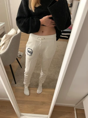 Vita mjukisbyxor från GANT med tryck - Snygga vita mjukisbyxor från GANT med svart tryck på ena benet. Storlek 158/165. Finns några små fläckar på baksida ben (se sista bilden) men detta är inget som syns så mycket vid användning. 