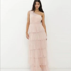 Ljusrosa omlottklänning med volanger - Säljer denna otroligt fina balklänning i rosa med volanger och one shoulder-design. Den är endast använd en gång och är i mycket fint skick. Kemtvättad och ser ut som ny – perfekt för bal, bröllop eller annan fest! 💕 