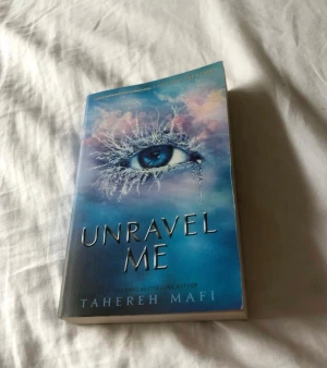 Unravel Me - En bok med ett mystiskt omslag där ett öga med frostiga detaljer fångar blicken. Perfekt för dig som gillar spännande och känsloladdade berättelser. Passar unga vuxna som söker något utöver det vanliga.