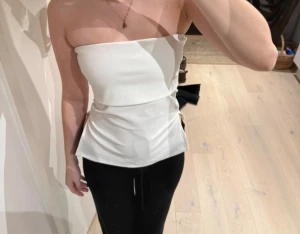 Vit tubtopp från Gina Tricot - Säljer en vit bandeau tubtopp från Gina Tricot i storlek XS. Toppen är ärmlös och har en slät, lätt ribbad struktur med en snygg slits i båda sidorna. Materialet känns mjukt och stretchigt. Har använt den 2 gånger 