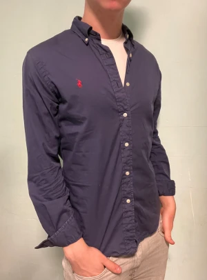 Ralph Lauren skjorta blå - Säljer denna stilrena och snygga blå Ralph Lauren skjorta. Skjortan är i  bra skick. Modellen är M slim fit. Obs tvättlappen är avklippt Har du några frågor? Tveka inte att höra av dig. Allt gott från Deluxe garderoben ⭐️