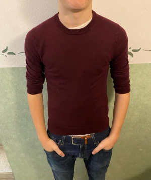 Vinröd merinoullströja från Riley - Snygg vinröd tröja från Riley i mjuk merinoull. Modellen är klassisk med rund hals och långa ärmar, perfekt för dig som gillar stilrena och bekväma plagg. Passformen är slim och färgen är djup vinröd som ger en schysst vibe till din outfit.