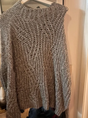 Grå stickad tröja med grovt mönster - Säljer en grå stickad tröja med grovt och luftigt mönster. Tröjan har långärmade ärmar och en rund halsringning. Perfekt för dig som gillar en chill och cozy vibe under kyliga dagar.