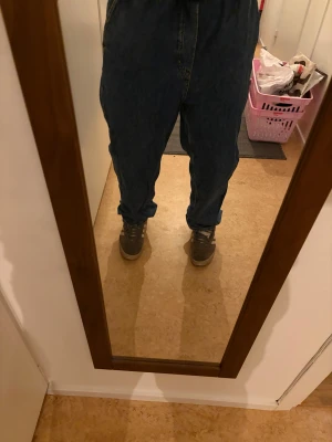 Blå baggy jeans med snörning - Säljer ett par blå jeans med baggy passform och elastisk midja med snörning. Jeansen har en avslappnad look och är tillverkade i klassiskt jeansmaterial. Perfekta för dig som gillar loose fit och vill ha bekväma byxor med streetkänsla.