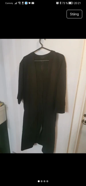Svart långklänning från Topshop - En svart långkofta från Topshop i enkel och clean design. Koftan har trekvartsärm, rak passform och ett bälte i midjan för att skapa snygg siluett. Perfekt för dig som gillar minimalistisk stil.