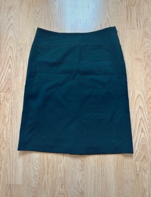 Svart pennkjol från Mexx - En klassisk svart pennkjol med enkel design rak passform. Kjolen är knälång och har en diskret dragkedja i sidan. Kjolen är stilren och lätt att matcha med olika toppar. Perfekt för dig som gillar minimalistisk stil och vill ha en kjol som funkar till många olika looks