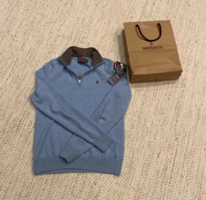 Ljusblå half zip tröja Morris - Snygg ljusblå tröja från Morris med half zip och brunt ribbat krage. Tröjan kommer med original påsa och tags medföljer! Tröjan ör i storlek xs och kommer sitta dunder på en grabb som är 160-165! Inga defekter alls på tröjan ! Pris kan diskuteras 