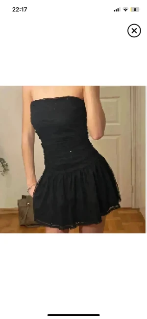 Perfekta jul/nyårsklänningen🎄🎅 - Supersnygg svart kort klänning med glittriga paljetter och volang nedtill. Klänningen är axelbandslös men har även smala axelband som kan användas. Materialet är lätt och har en mesh-liknande känsla med paljettdetaljer som ger extra bling. Perfekt för dig som vill sticka ut.