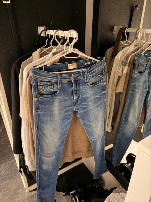 Replay ” Anbass ”  jeans  - Säljer ett par Replay Anbass jeans i ljusblå tvätt med snygga slitningar. Jeansen har Replay-logga på myntfickan och bakfickan, samt patch bak i midjan. Perfekta för dig som gillar en modern och stilren look. Byxorna är i ett väldigt bra skick!