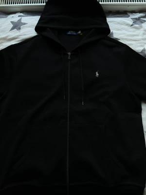 Ralph Lauren - Säljer en Polo Ralph Lauren i storlek XXL med mörkgrå logga som jag fick som födelsedagspresent för ett tag sedan. Koftan är för stor och har bara legat i mitt rum utan någon användning. Har bara provat koftan!