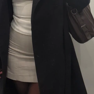 Beige kortkjol med stilren look - Snygg beige kortkjol med rak passform och minimalistisk design. Kjolen har en slät yta utan mönster och passar perfekt till en enkel topp eller kavaj. Materialet känns mjukt och följsamt mot kroppen, vilket gör den bekväm att bära hela dagen.