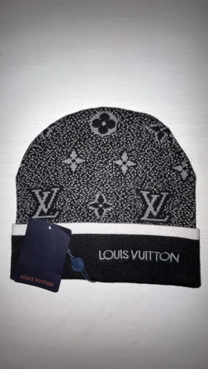Lv mössa - Snygg svart och grå mössa från Louis Vuitton med klassiskt monogrammönster och logotyp broderad framtill. Perfekt för vintern😁🤩
