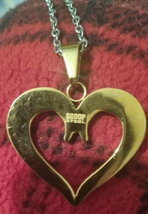 Guldigt hjärthalsband från Scoop Steel - Unikt halsband med ett stort, öppet hjärta i guldton från Scoop Steel. Hängs i en grov silverfärgad kedja. Perfekt statement-piece för dig som gillar att sticka ut med coola smycken och hjärtformade detaljer. Ej silver. 