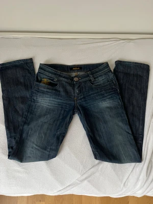 Mörkblå jeans från Killah - Snygga mörkblå jeans från Killah.  Klassisk femficksmodell med guldfärgade detaljer på fickorna och raka ben. Storlek xs-S PRISET KAN DISKUTERAS!!