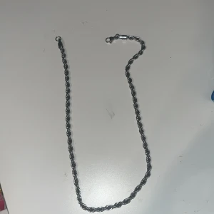 Tvinnad silverfärgad halskedja - Snygg halskedja i silverfärgad metall med tvinnad design och klassisk karbinlås. Kedjan har en stilren look som passar perfekt till streetwear eller för att lyfta din outfit. Längden är lagom för att bäras både ensam eller med andra smycken.Pris kan diskuteras…