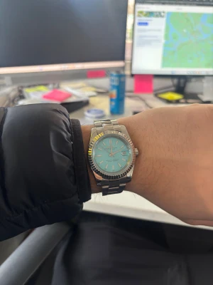 Seiko Oyster Datejust - Säljer en Seiko Oyster Perpetual Datejust med turkos urtavla och datumvisning. Klockan har en rund boett i silverfärgat stål och en klassisk länkarmband i metall. Automatisk rörelse syns genom bakboetten. Stilren och modern design som sticker ut och blänker. Denna är en modd klocka från bara seikos delar. Extra länkar tillkommer!