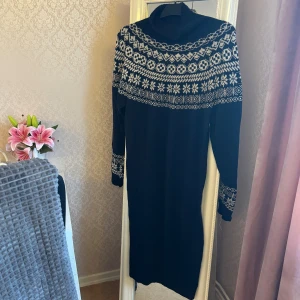 Mörkblå stickad sweatshirtklänning - Mysig mörkblå stickad klänning med vit nordisk-inspirerad mönsterstickning över bröst, axlar och ärmslut. Klänningen har polokrage och långa ärmar, perfekt för kyliga dagar. Modellen är rak och går ner till knäna. Köpt ett par år sedan, storlek finns inte med på lappen men bedömer att det är en L — passar perfekt som en ovserzied sweatshirt på mig som är en S/M. 😊
