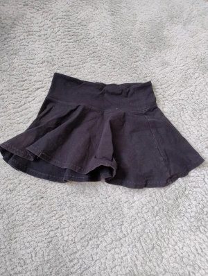 Svart minikjol från Marwin - Säljer en svart minikjol från Marwin med utsvängd form och bred linning. Kjolen är tillverkad i mjuk bomull och har en enkel, stilren look utan mönster eller extra detaljer. 