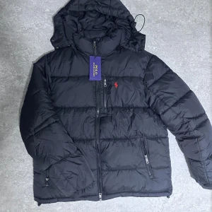 Svart pufferjacka från Polo Ralph Lauren - Svart pufferjacka från Polo Ralph Lauren i storlek L (funkar även för M). Det finns även en QR-kod för att bekräfta äkthet. Vid frågor är det bara att höra av sig.