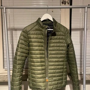 Save the duck jacka  - Säljer nu denna gröna stilrena jacka pga den blivit för liten. Denna jacka kommer ge dig många komplimanger eftersom den passar till alla outfits. Användes lite då och då när den väl passade men skicket är som ny utan prislapp bara.                                                                     Storlek: M                                                                Pris: kom med bud om det ej passar (ny pris 1600kr) 