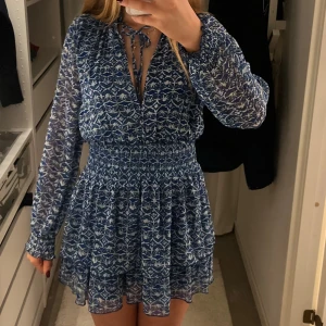 Blåvit mönstrad klänning från Zara - Supersöt blåvit kortklänning från Zara❣️ långa ärmar och v-ringning med knytband och volangig kjol. 😊❤️perfekt till sommaren utomlands och Sverige❣️ pris kan diskuteras!!