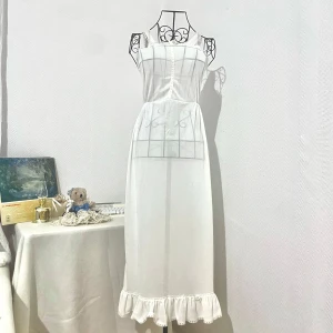 Vit långklänning med spets och volang - Säljer en romantisk vit långklänning med smala axelband och spetsdetaljer. Ganska genomskinlig. Passar bra som en underklänning eller vanlig klänning när man matcha med andra plagg och underkläder. Ger en ”vintage” och ”cottagecore”-känsla. Storlek: XS (32-34). Dockans storlek: 34. MADE IN U.S.A. Se märke i sista bild.