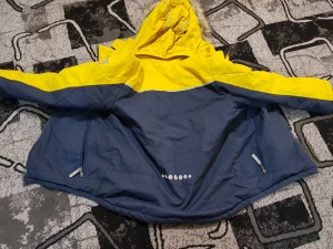 Blå och gul parkajacka med päls - Säljer en blå och gul parkajacka från Didriksons med huva och fuskpäls. Jackan har dragkedja, två fickor med dragkedja och reflekterande detaljer på ryggen. Insidan är fodrad och jackan har en loose passform, perfekt för kalla dagar.Den går bra för barn. 