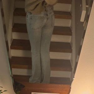 Ljusblå bootcut jeans med slitningar - Säljer ett par ljusblå jeans med snygga slitningar och tvättade detaljer framtill. Modellen har bootcut-ben och klassisk femficksdesign. 