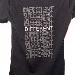 Svart Moncler t-shirt - Svart t-shirt från Moncler med coolt tryck på ryggen där ordet 'DIFFERENT' upprepas i vitt och på framsidan står det 'SAME BUT'. Klassisk rund hals och korta ärmar. Mjuk bomullskvalitet som känns skön mot huden. Perfekt för dig som gillar statement-plagg.