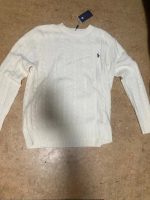 Vit stickad tröja Polo Ralph Lauren - Snygg vit kabelstickad tröja från Polo Ralph Lauren i storlek XXL. Aldrig använt då den tyvärr är för stor för mig.