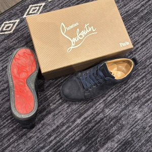 Christian Louboutin - Snygga mörkblå sneakers från Christian Louboutin i mocka med klassisk röd sula. Skorna har rund tå, platt sula och snörning. Kommer med originalkartong, dustbag och papper. Perfekta för dig som vill sticka ut med exklusiv stil.                  Kan även göra rent sulan☺️                                              (Är storlek 41 men passar som 42)