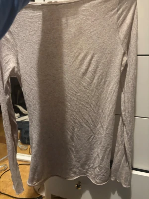  Intemissme. Ljusbeige långärmad topp - En enkel och stilren ljusbeige långärmad topp med rundad hals. Tunn och mjuk i materialet, perfekt för lager-på-lager eller att bära som den är. Passformen är normal och toppen har en clean look utan mönster eller detaljer.