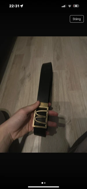 Svart skärp med guldspänne donken  - Säljer ett svart bälte med ett unikt fyrkantigt guldspänne som har den ikoniska McDonald's-bågen. Bältet är brett och tillverkat i skinn, perfekt för dig som vill sticka ut med en cool detalj i outfiten.