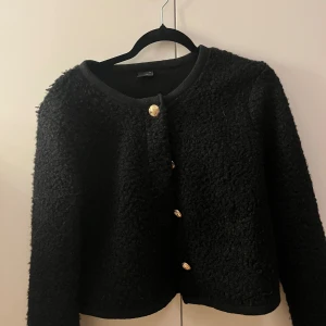 Svart teddyjacka med guldknappar - Fin lite tunnare jacka eller kan användas som kofta, från Gina tricot. Använd fåtal gånger. Super fin och skön