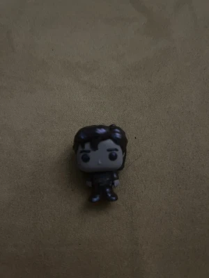 steve funky pop kinderjoy - Bilden visar en liten figur, troligen en samlarleksak eller Funko Pop-liknande figur. Produkten är inte elektronik och saknar synliga tekniska specifikationer, märke eller modell. Inga defekter eller slitage syns tydligt.