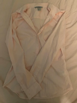Ljusrosa skjorta från H&M - Säljer en ljusrosa skjorta från H&M i storlek 36. Skjortan har klassisk krage, långa ärmar och knäppning framtill. Tillverkad i mjuk bomull som känns skön mot huden. Perfekt att styla med jeans eller kjol för en clean look.