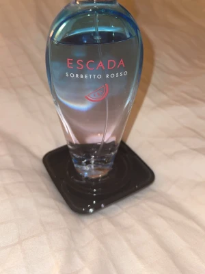 Escada Sorbetto Rosso parfym - Fräsch och färgstark parfym från Escada med en lekfull design. Perfekt för dig som vill ha en unik och trendig doft i samlingen. Flaskans utseende sticker ut och passar dig som gillar att synas.