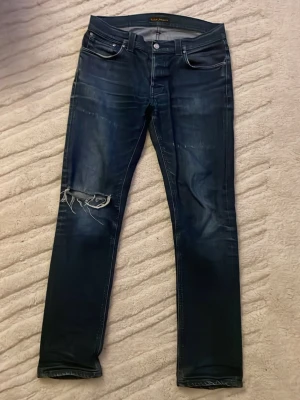 Nudie Grim Tim - Säljer ett par Nudie Grim Tim med snygga fades, skicket är jätte bra förutom hålet på knät som är där för design. Fråga om mått/mer bilder