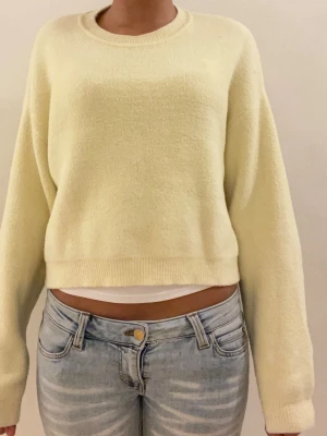 Ljusgul stickad tröja från Zara - Supermysig ljusgul stickad tröja från Zara med långa ärmar. Tröjan har rund halsringning och ribbade muddar vid ärmslut och nederkant. Tröjan har haft ett litet hål på sidan som sytts igen. Men det syns knappt!💛