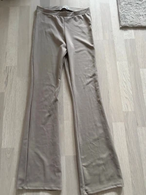 Beiga bootcut byxor oanvända! - Säljer ett par snygga beiga bootcut byxor från 157. De har hög midja och är gjorda i ett mjukt, stretchigt material som känns skönt mot huden. Perfekta till sneakers eller boots och superlätta att styla till olika looks. Oanvända pga fel storlek 
