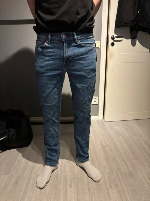 Blå regular fit jeans från H&M - Säljer ett par klassiska blå jeans från H&M i regular fit. Jeansen har raka ben, fem fickor och normal midja. Tillverkade i slitstarkt denimtyg med snygga kontrastsömmar. Perfekta till vardags och passar till det mesta.
